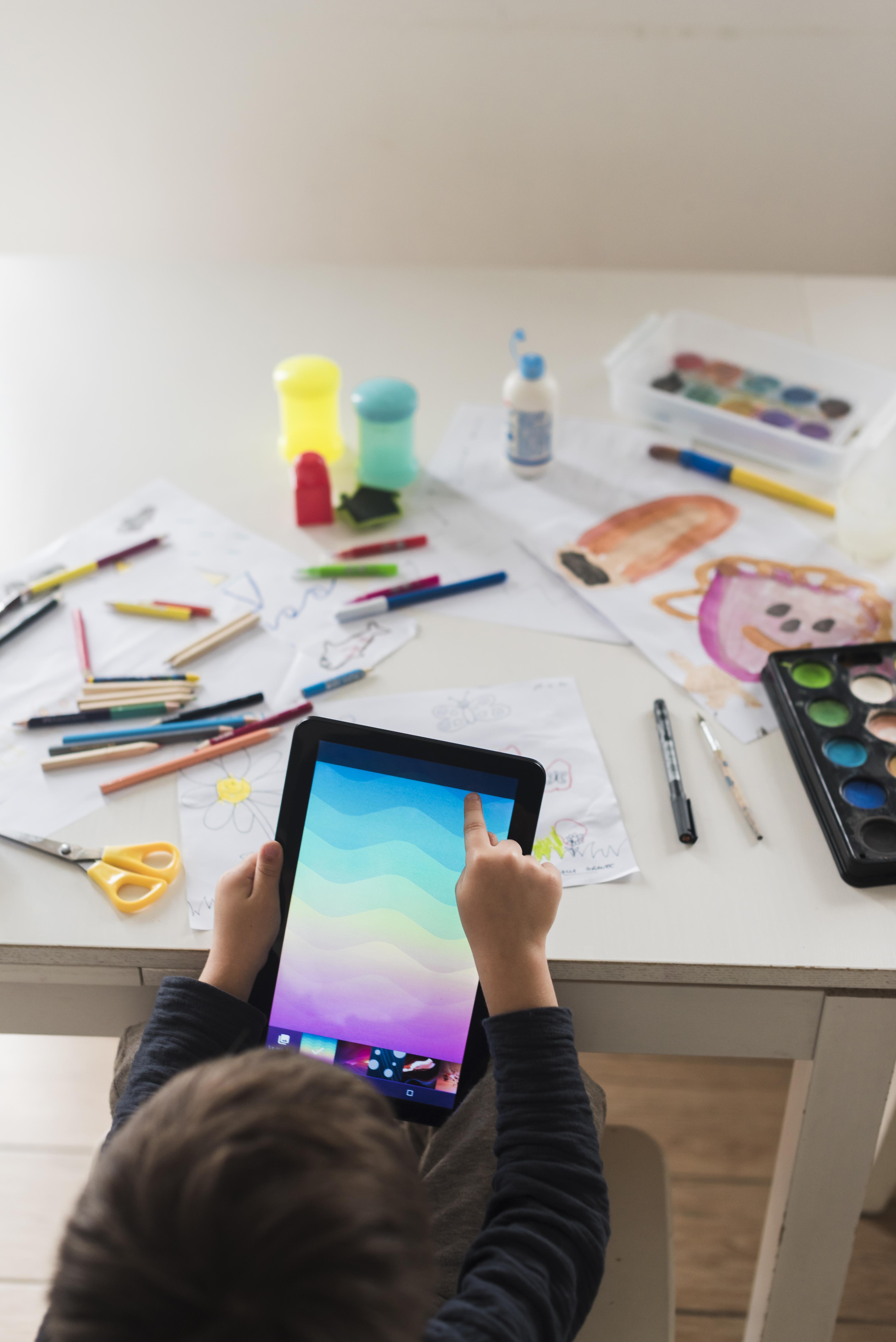 enfants regardant une tablette tactile sur ca table de dessin